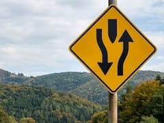 Qué significa la señal de tránsito con dos flechas en sentidos opuestos alrededor de un separador central y por qué es importante reconocerla