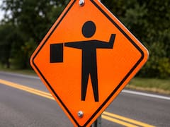 Qué significa la señal de tránsito naranja con una persona sosteniendo una bandera y qué deben hacer los conductores cuando la ven