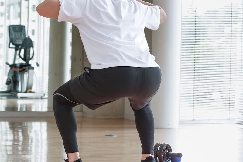Hombre joven entrena glúteos en el gimnasio haciendo sentadillas