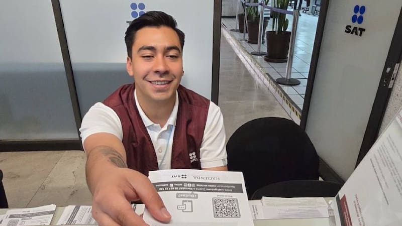 Servidor del SAT atendiendo por ventanilla y entrega un documento de quejas y reclamos.