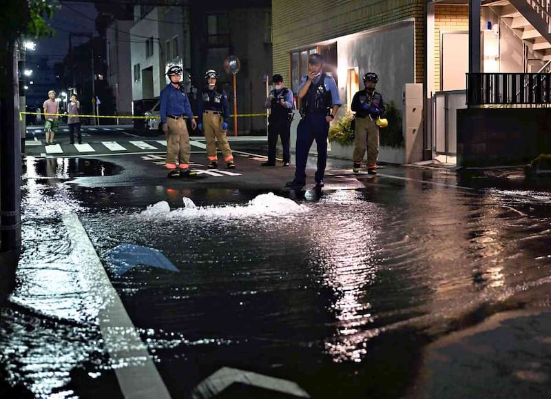 Bomberos trabajan en una tubería de agua que reventó tras un terremoto en el distrito de Koto, Tokio.