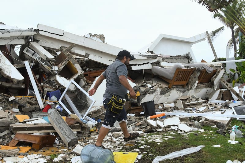 AME442. IZTAPA (GUATEMALA), 10/06/2026.- Una persona camina entre escombros de viviendas destruidas debido al fuerte oleaje y constantes lluvias generadas por la tormenta tropical Cristina este miércoles, en el puerto de Iztapa (Guatemala). Guatemala tiene más de 800 puntos de riesgo a deslaves e inundaciones, entre otros, según cálculos oficiales. EFE/ Alex Cruz