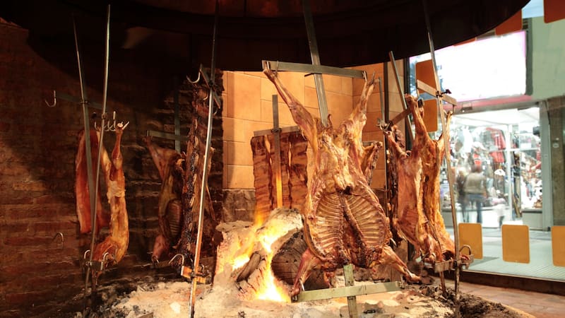 View of Argentine grilled meat Baby goat, Pork, Crosscut ribs and Rump steak on big flame of fire at a traditional Argentinean restaurant in Buenos Aires, Argentina