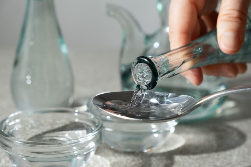 Una persona mezclando agua con vinagre.