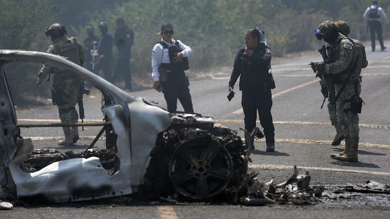 Integrantes de la policía de Morelia y del ejército trabajan en la zona donde fue incendiado un vehículo por presuntos integrantes del crimen organizado este domingo.